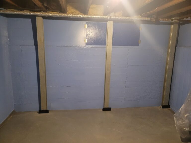 Steel braces installed against a painted block basement wall