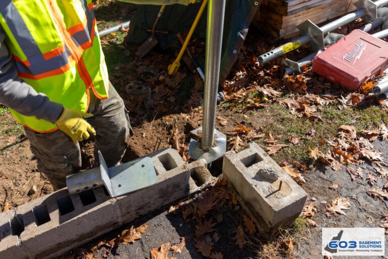 Steel helical-pier bracket set against the foundation footing