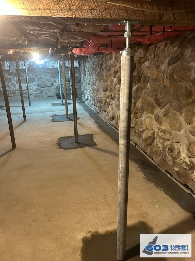 New adjustable steel lally column set on a poured footing in a 603 fieldstone basement