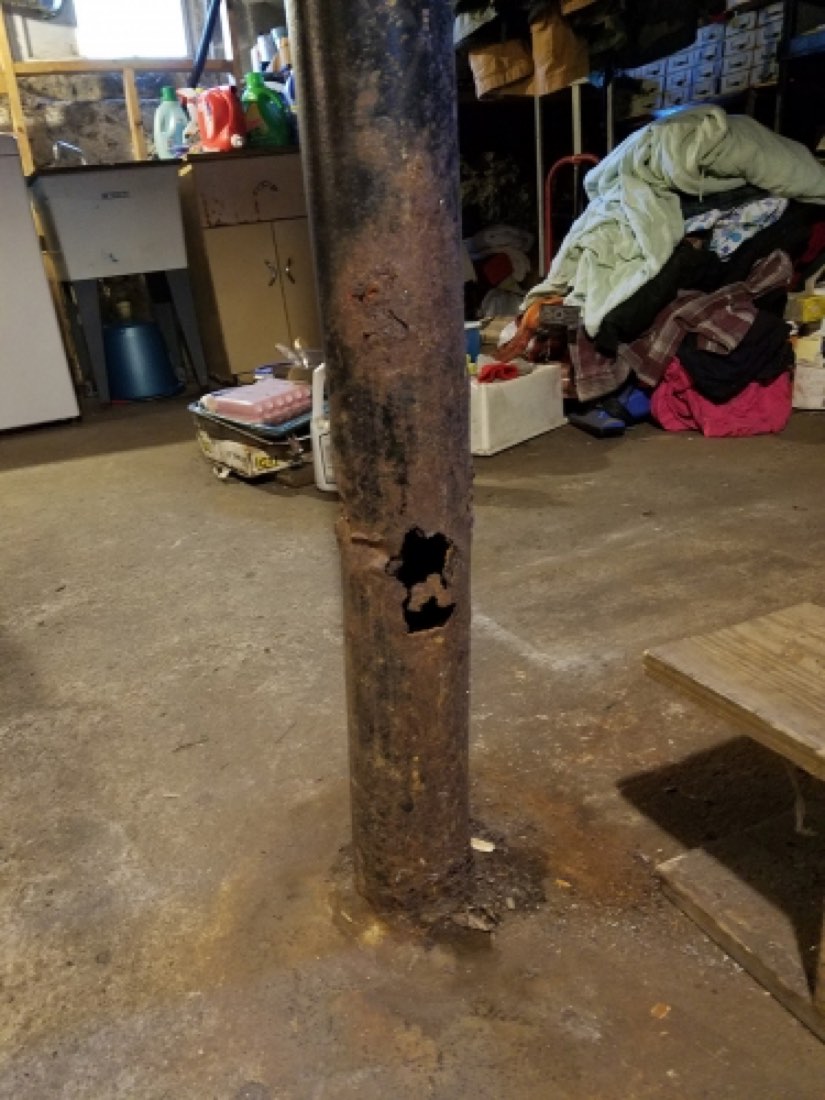 Steel lally column rusted through at the base, open hole in the pipe, basement.