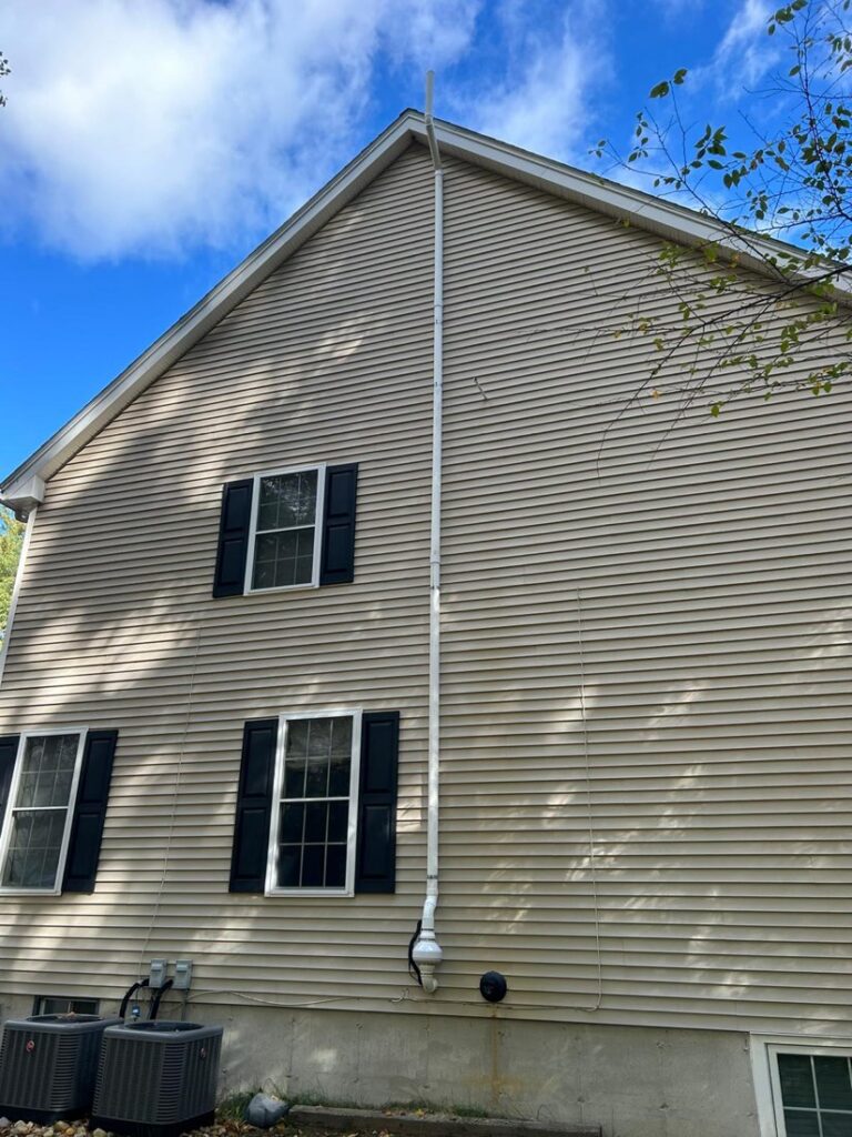Exterior radon mitigation vent pipe routed above the roof edge