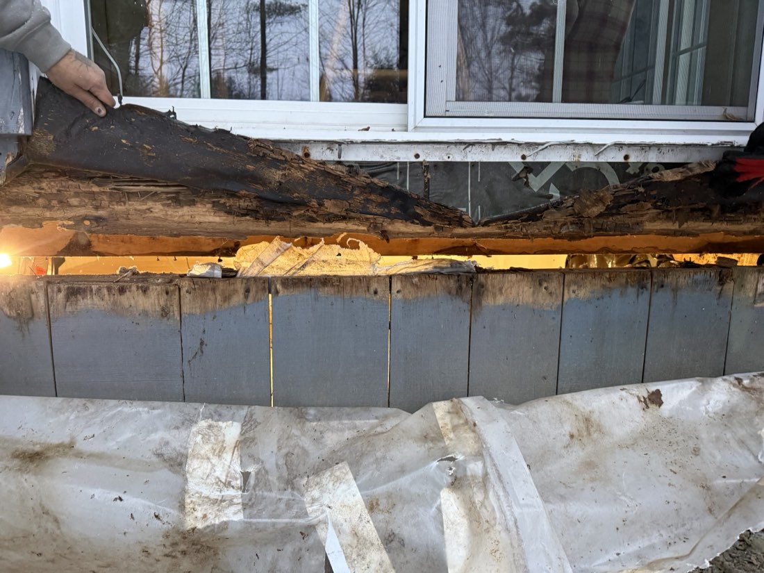 CORRECTED: a crew member pulling a rotted, delaminating sill section away from the rim. This is demolition, NOT finish