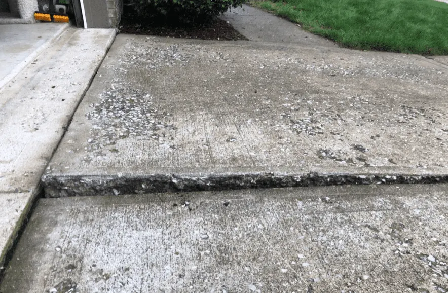 Raised joint between concrete driveway panels near a garage